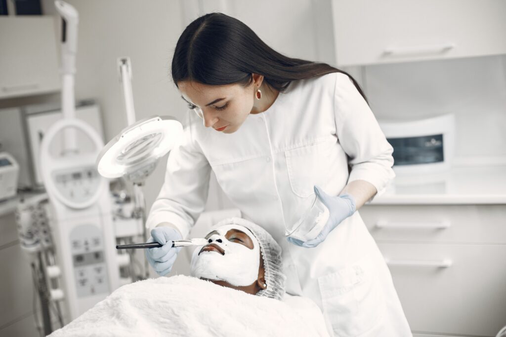 A beautician applies a face mask to a client in a beauty clinic, focusing on skincare and relaxation.